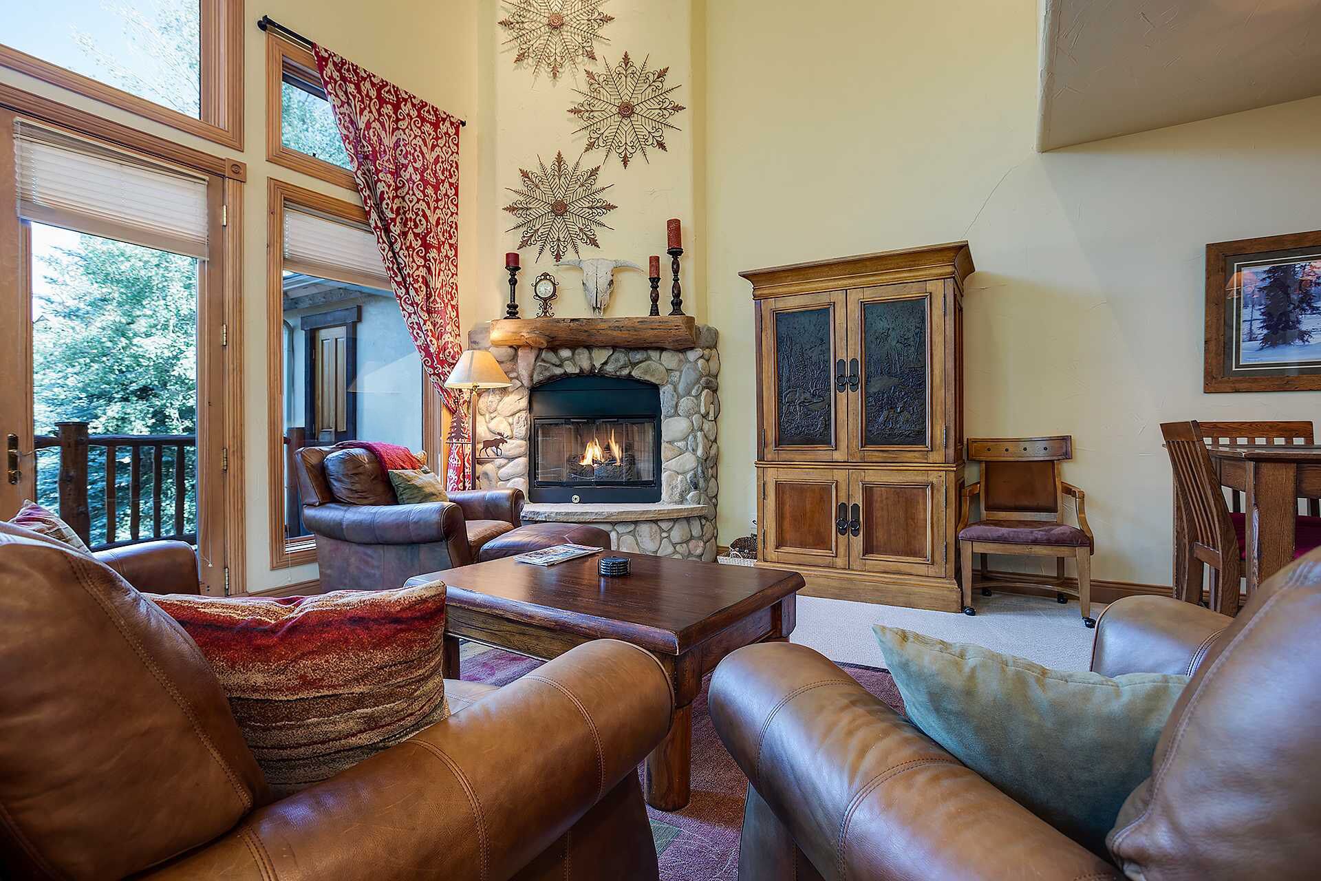 Una sala de estar acogedora con muebles de cuero, una chimenea de piedra y un mueble grande.