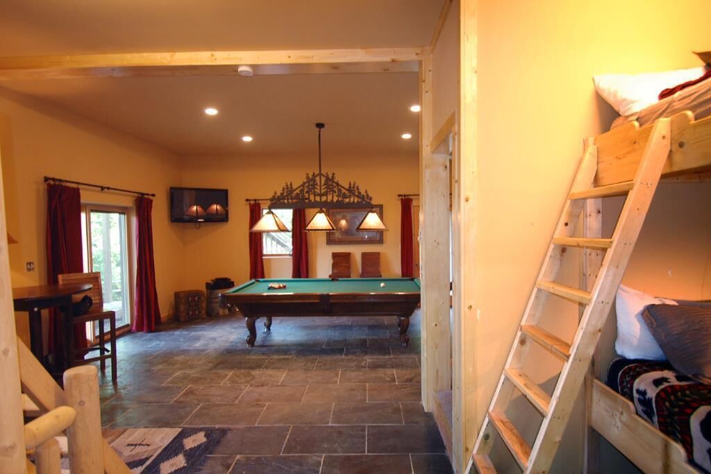 A room with a pool table, a wooden ladder, and a billiards setup.
