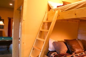 A bunk bed with a wooden ladder, a pool table, and a billiard cue.