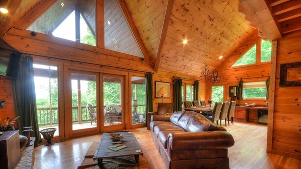Una cabaña espaciosa con una amplia sala de estar, pisos de madera y un comedor con vistas al exterior.
