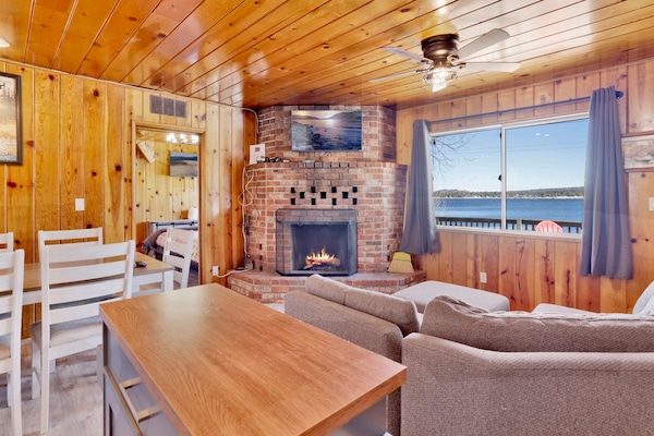 Cozy cabin living room with a stone fireplace, comfy seating, and rustic wood details—perfect for relaxing evenings, movie nights, and unforgettable mountain getaways.