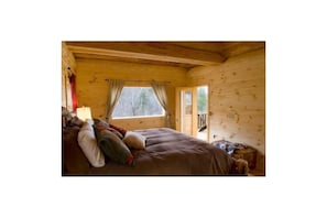 Cozy cabin with a bed, window, and door leading to an outdoor area.