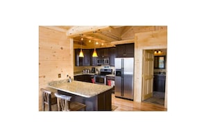 Enjoy cooking in this well-equipped kitchen with a central island, sink, and bar stools.
