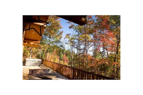 Relax on the deck with a hot tub overlooking the forest, surrounded by vibrant autumn foliage.