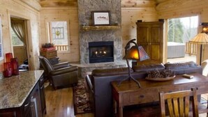 A cozy cabin interior with a stone fireplace, wooden walls, a dining area, and a seating area. - Stargazer - Free Train Tix + Modern-Rustic Cabin (Bryson City)