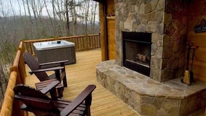 A wooden deck with a stone fireplace and a hot tub. - Stargazer - Free Train Tix + Modern-Rustic Cabin (Bryson City)