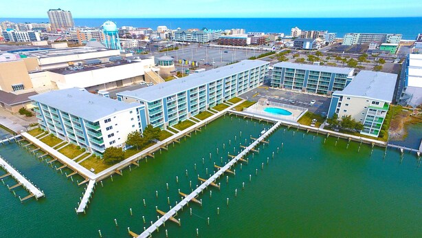 A modern hotel with a marina, featuring multiple buildings, a dock, and a view of the ocean. - Thunder Island 10A-Baywater 39th St, Pool, Elev, W/D, AC (Ocean City)
