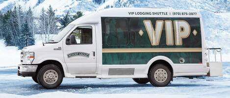 A white RV with 'RESORT GROUP' branding and 'VIP LODGING SHUTTLE' text, parked on a snowy road.