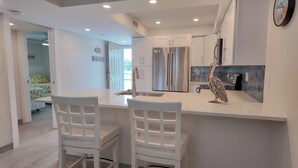 Cocina moderna con armarios blancos, electrodomésticos de acero inoxidable y una escultura decorativa de pelícano en la encimera.