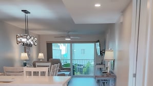 Una cocina moderna con lavavajillas, comedor con mesa y sillas, y vistas al exterior a través de amplios ventanales.
