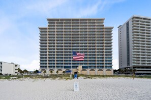 A hotel with a large American flag, multiple floors, and a beach view.