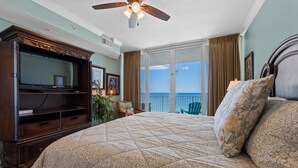 Ein Schlafzimmer mit einem großen Bett, einem Deckenventilator, einem Fernseher und einem Balkon mit Blick.