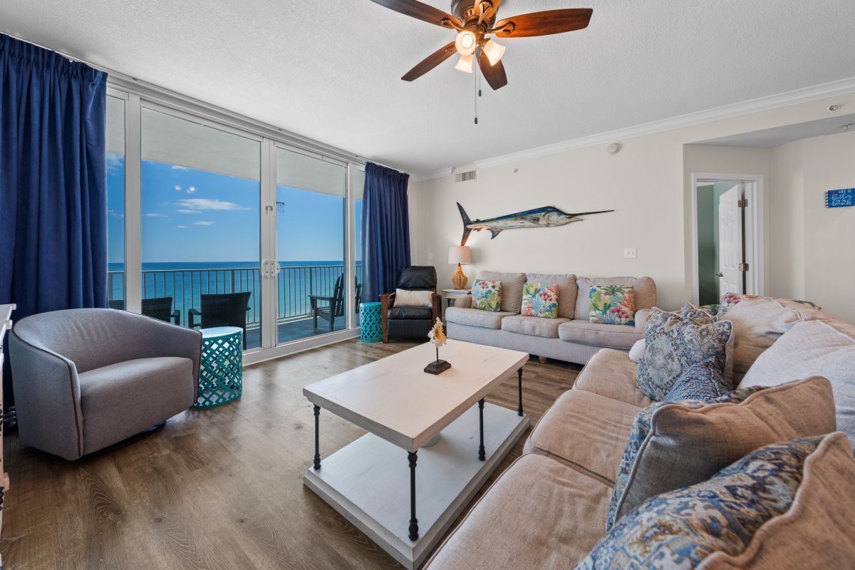 A living room with a sofa, armchair, coffee table, and a ceiling fan.
