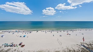A beach with a volleyball net, umbrellas, and a flag. - San Carlos Condo | Beachfront w/ Pool, Sauna, and Fitness Center | Sleeps 10 (Gulf Shores)