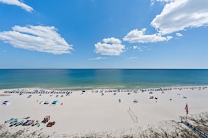 A beach with a volleyball net, umbrellas, and a flag. - San Carlos Condo | Beachfront w/ Pool, Sauna, and Fitness Center | Sleeps 10 (Gulf Shores)