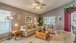 A living room with a ceiling fan, two sofas, a coffee table, and a floor lamp. - Enjoy In Pool Dining, Hot Tub & Games Rm. Disney 4 Miles. Pet Friendly (Kissimmee)