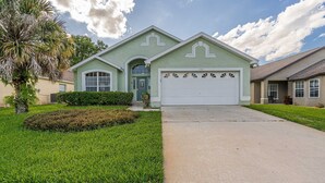 A single-story house with a green facade, a garage, and a well-maintained lawn. - Enjoy In Pool Dining, Hot Tub & Games Rm. Disney 4 Miles. Pet Friendly (Kissimmee)