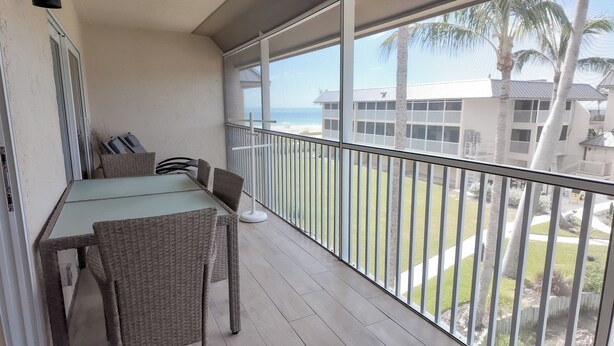 Een balkon met een tafel en stoelen, met uitzicht op een gebouw en een gazon.