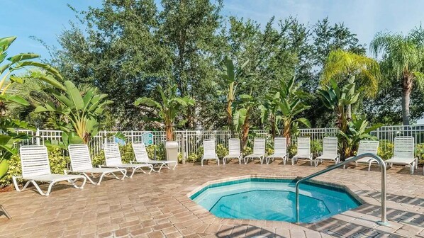 Relax by the pool surrounded by lush greenery and comfortable lounge chairs.