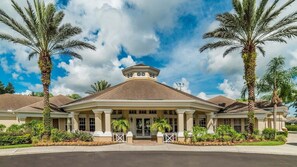 Stately building with a central entrance, flanked by palm trees, and a prominent gabled roof.