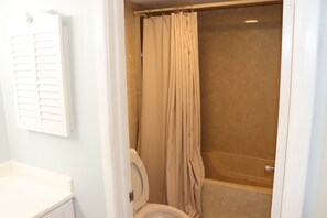 Een badkamer met een toilet, een douche en een bad.