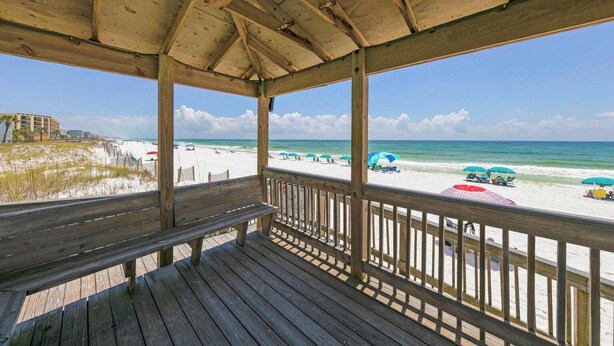 A wooden deck with a view of the beach and ocean.