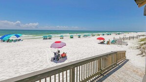 A beach with a wooden deck and beach umbrellas.