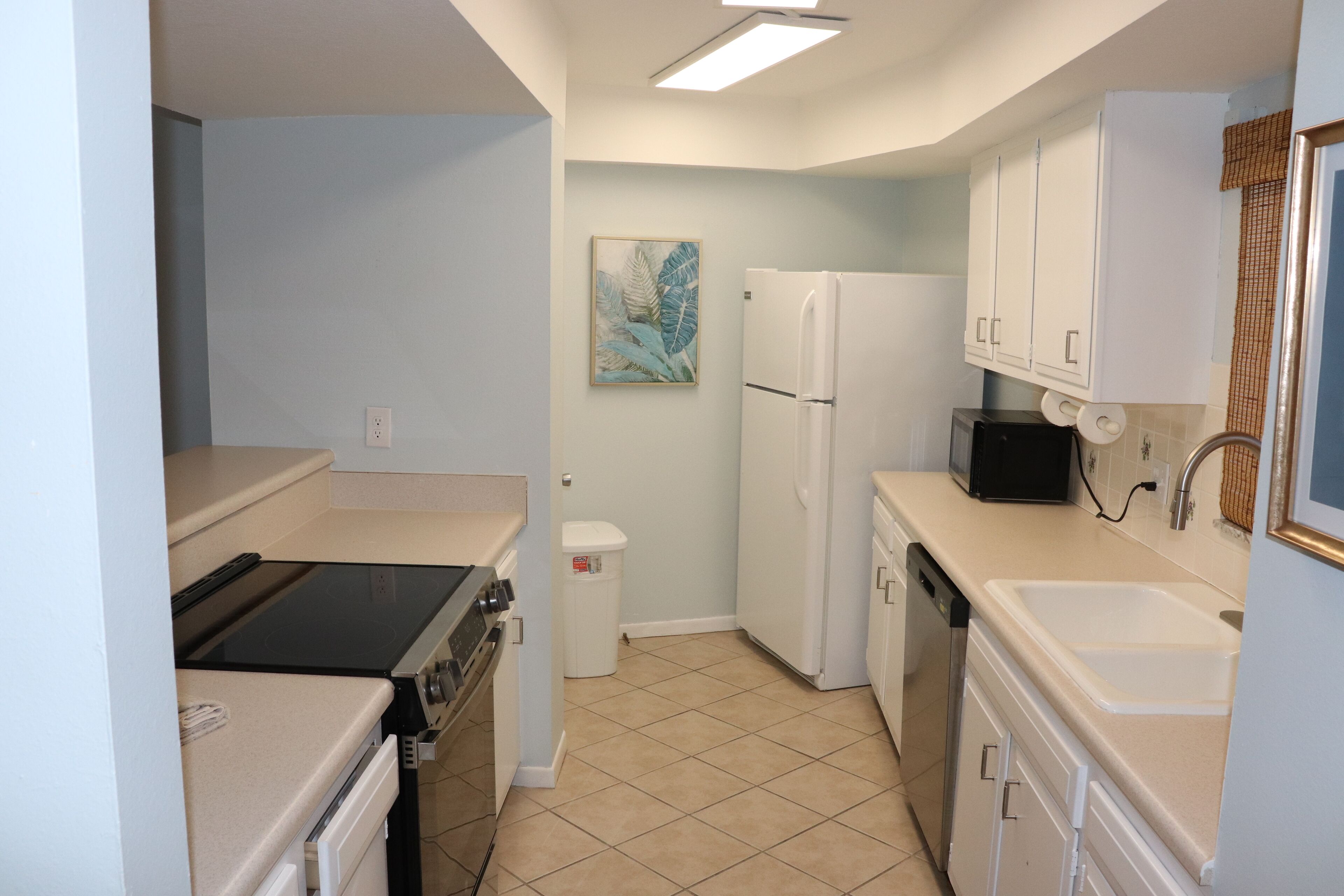 A compact kitchen with a refrigerator, microwave, stove, sink, and cabinets.