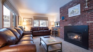 Una sala de estar acogedora con sofás de cuero, chimenea y televisor.