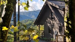 A log cabin with a wooden porch and a view of mountains in the background. - Romantic Cabin,Views,Pet-Friendly,Trails (Ferguson)