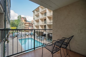 A balcony with a pool, outdoor furniture, and a view of a building with multiple balconies. - Oak Square 108 is a lovely condo with private balcony overlooks pool in downtown (Gatlinburg)