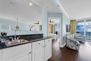 A modern kitchen with a black countertop, white cabinets, and a large window. - Luxury Beachfront Condo w/ Pool & Sauna | Gulf Shores | Sleeps 10 (Gulf Shores)
