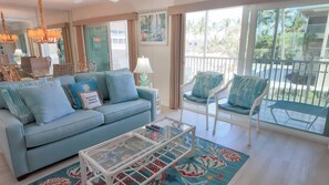 A living room with a sofa, chairs, a coffee table, and a view of the outdoors. - Steps To The Beach (Sanibel)