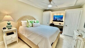 Une chambre à coucher comprenant un lit, une table de chevet, une lampe, un téléviseur et une armoire.