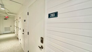 Un couloir avec les portes numérotées 203 et 304, dotées d’un cadenas à combinaison et d’un trou de serrure.