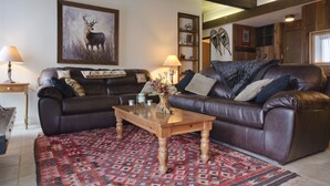 A cozy living room with a brown leather sofa, a wooden coffee table, and a patterned rug.