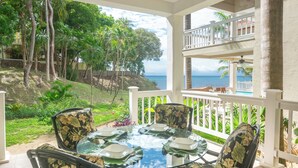 A glass-top table with floral chairs, a white railing, and a view of the ocean. - Pool, beach and sun- Parrot Fish 106 at Lawson Rock (Sandy Bay)