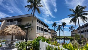 A resort with a pool, palm trees, and a thatched umbrella. - 5 Star Rated (Sanibel)