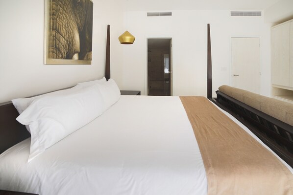 A hotel room with a large bed, a bench, a door, and a wall-mounted artwork. - Amazing Condo with big terrace & private pool-Mamitas Beach (Playa del Carmen)