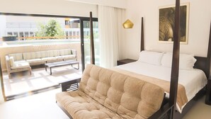 A bedroom with a four-poster bed, a sofa, and a view of a balcony with outdoor seating.
