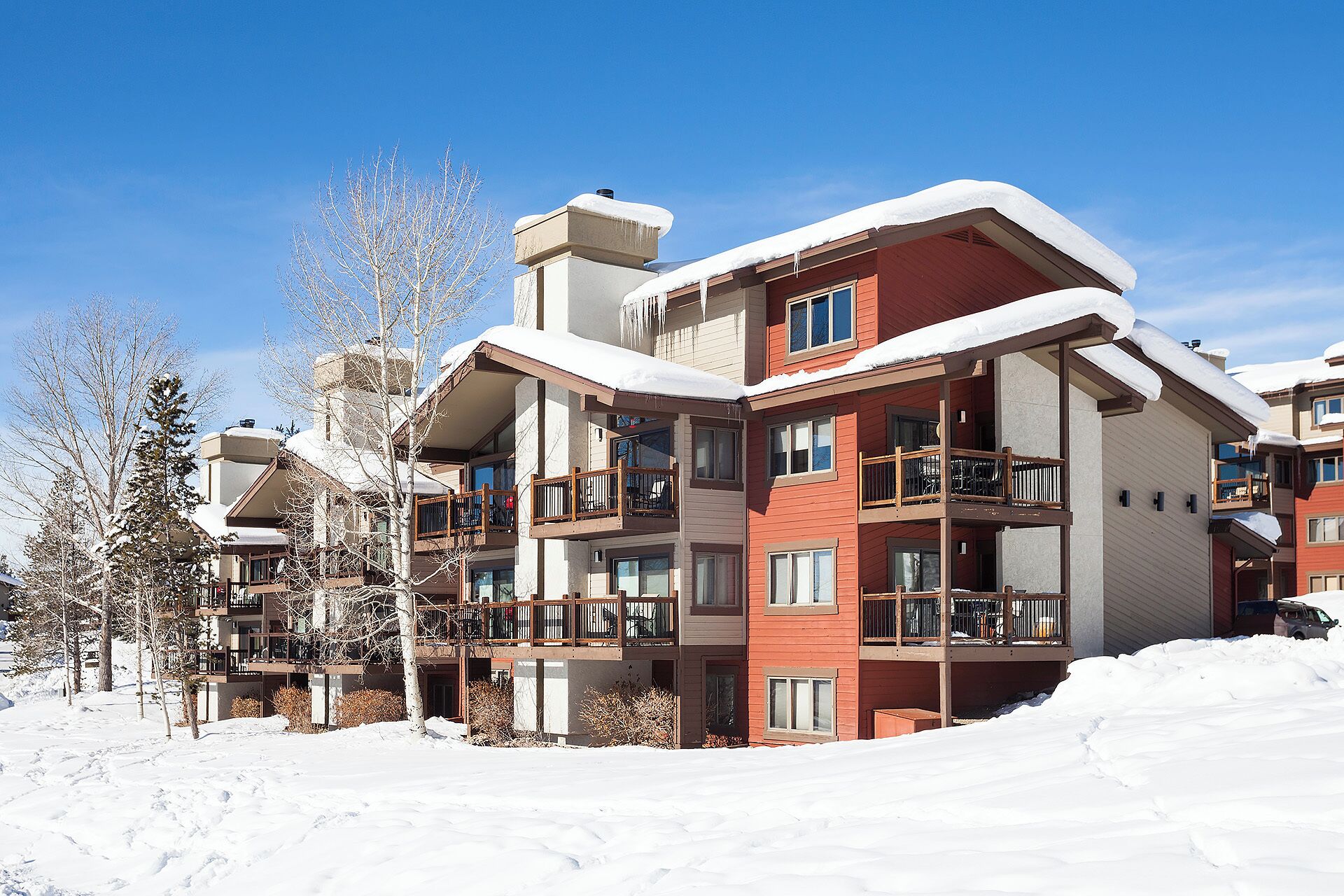 A multi-story hotel with balconies, snow-covered roofs, and a clear blue sky.