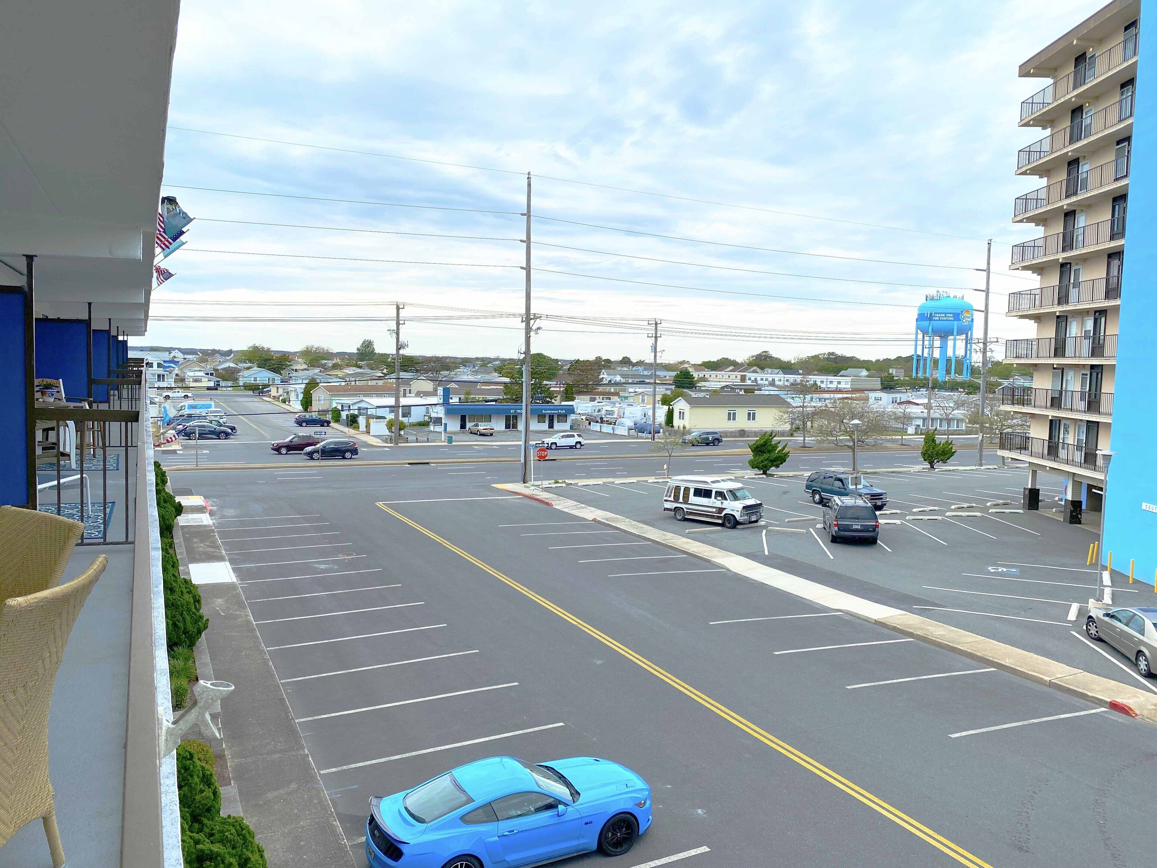 A parking lot with multiple cars, a water tower in the background, and a building with balconies.
