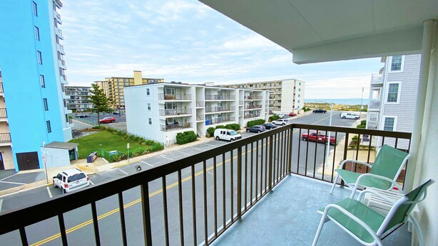 A balcony with a view of a parking lot and buildings. - Ocean Princess 207-Oceanside 134th St, Elev, W/D, AC (Ocean City)