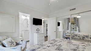 Quarto com cama, cómoda, televisão e espelho.
