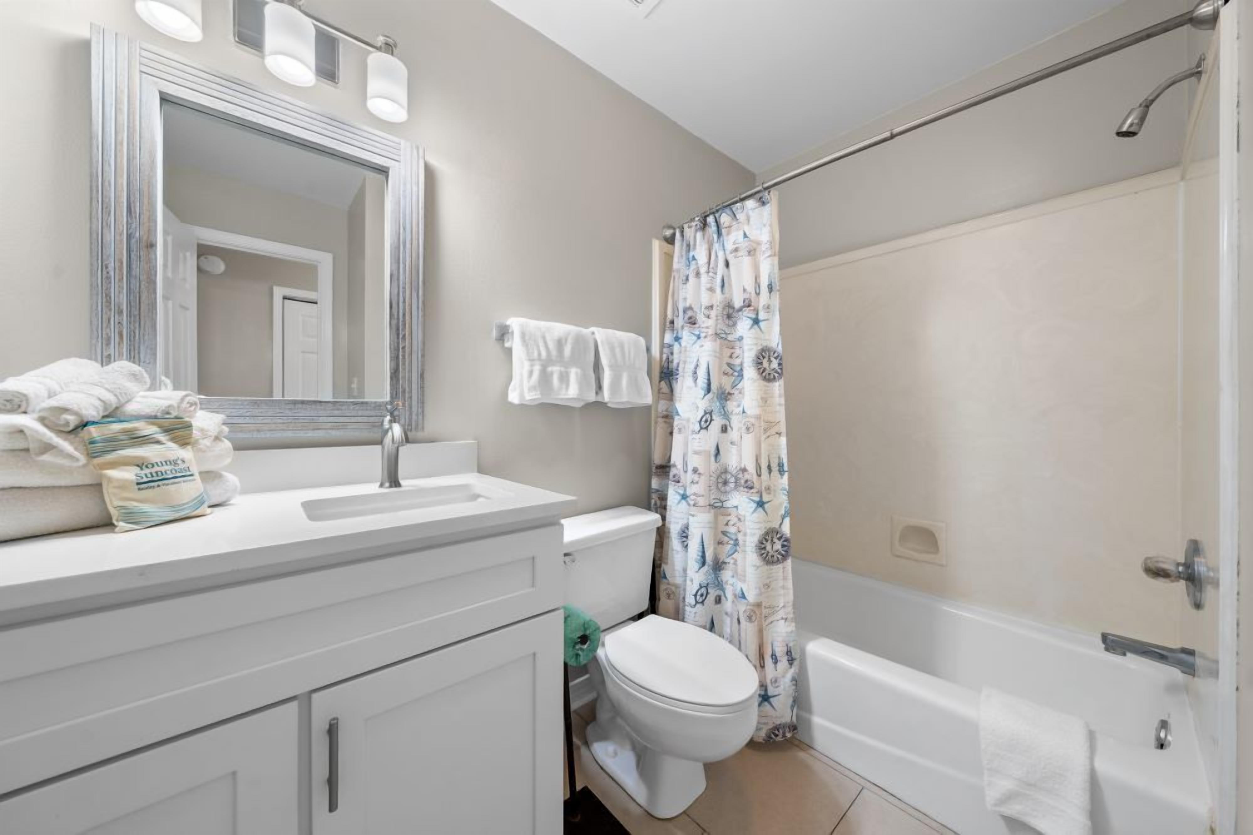 A bathroom with a sink, mirror, toilet, and bathtub.