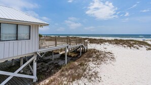 Une maison de plage dotée d’une terrasse en bois et offrant une vue sur l’océan.