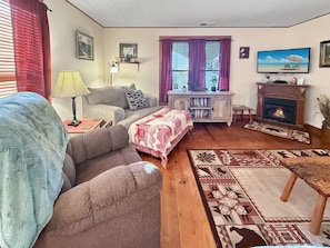 Ein Wohnzimmer mit einer Couch, einem Couchtisch, einem Kamin und einem Fernseher.