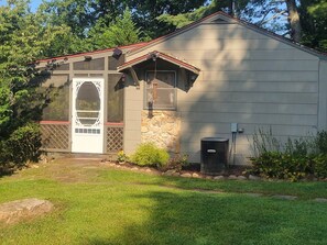 A single-story building with a stone foundation, a red roof, and a front door with a window. - Valley View Cottage - Quiet Cabin w/Firepit near Deep Creek and downtown + free railroad tix (Bryson City)