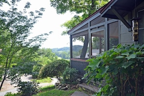 Ein Haus mit einem großen Fenster mit Blick auf eine üppige Landschaft.