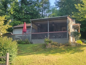 A house with a covered porch, a red umbrella, and a fenced yard.